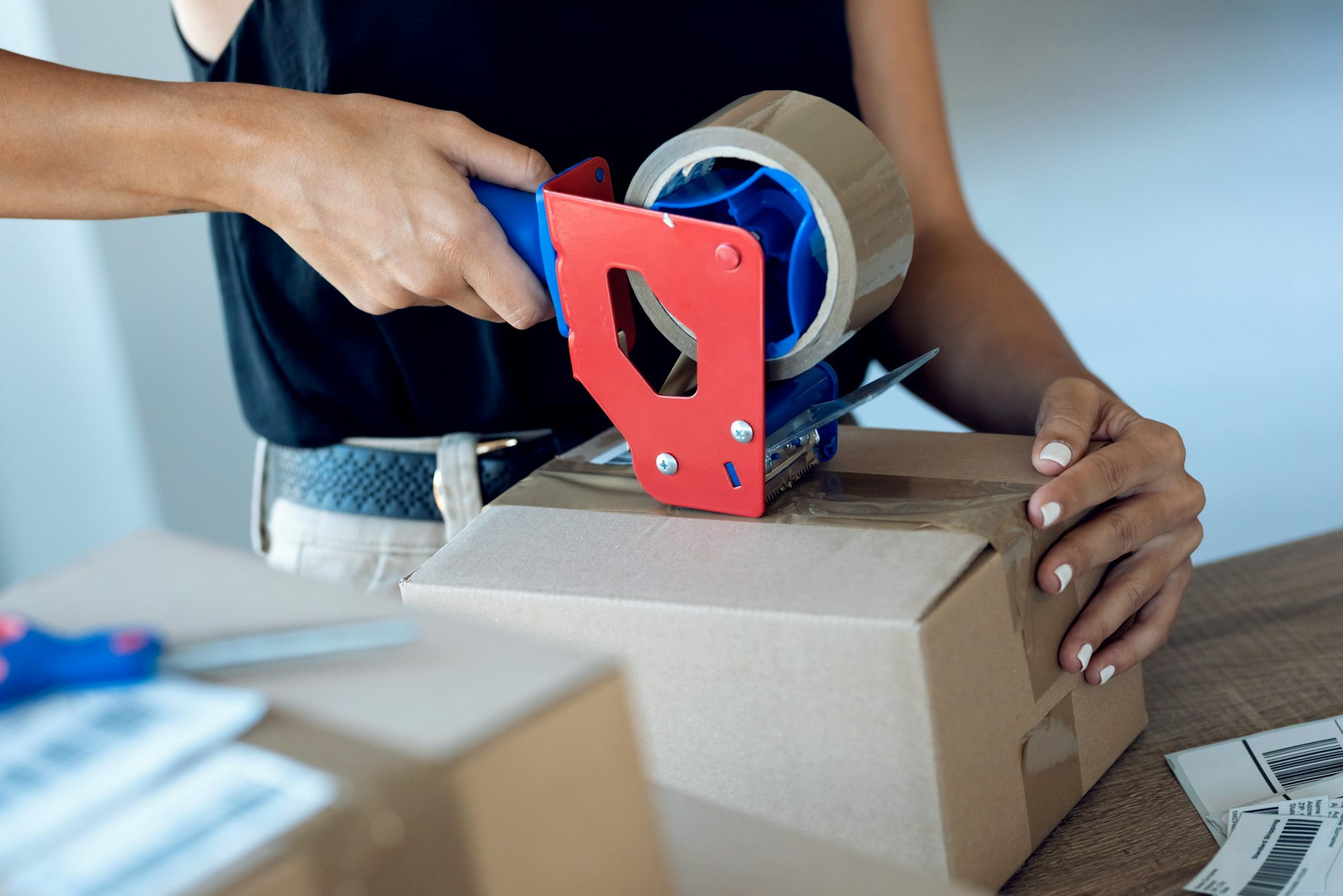 Close-up of young woman hands holding packing machine